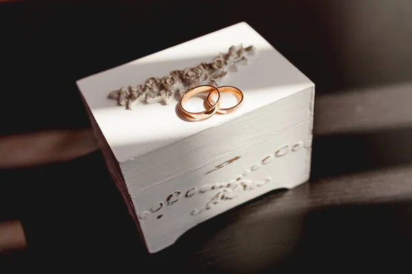 Par de anillos de boda dorados con diamantes en una caja decorativa blanca. Hermoso símbolo de amor y matrimonio . — Foto de Stock