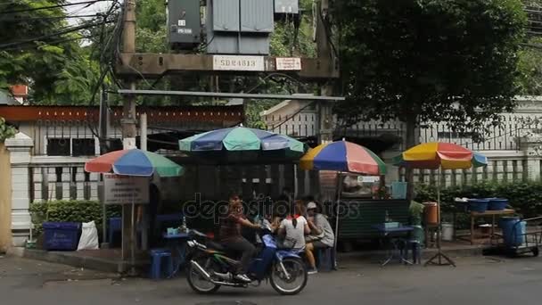 BANGKOK, TAILANDIA - 24 de octubre de 2012. Vida en la calle cerca del monte Wat Saket Golden. La gente conduce motos y coches, comer en el pequeño café al aire libre . — Vídeos de Stock
