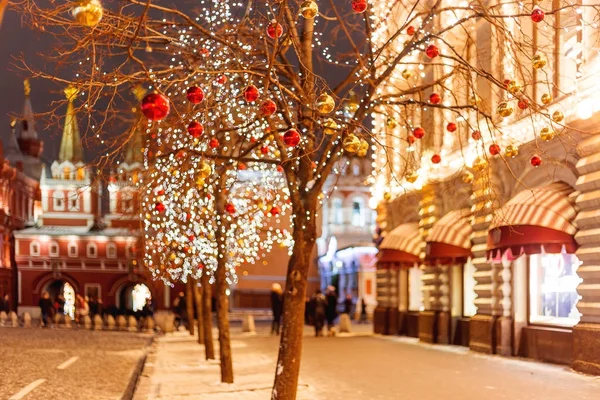 Улицы Москвы украшены к Новому году и Рождеству. Дерево с ярко-красными и желтыми шариками. Здания с лампочками . — стоковое фото