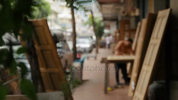 БАНГКОК, ТАИЛАНД - 24 октября 2012 года. Обычная жизнь на улице. Движение транспорта, ходьба людей. Рабочий шлифует деревянную дверь наждачной бумагой . — стоковое видео