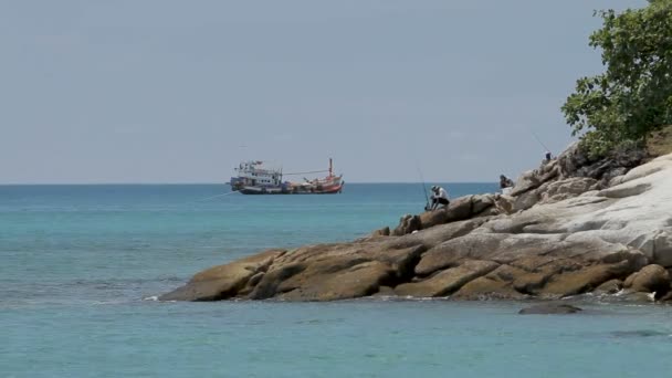 PHUKET, TAILANDIA - 18 de noviembre de 2012. Hombres pescando en la orilla. Barco de pesca balanceándose sobre las olas . — Vídeos de Stock