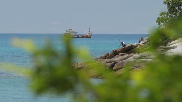 PHUKET, TAILANDIA - 18 de noviembre de 2012. Hombres pescando en la orilla. Barco de pesca balanceándose sobre las olas . — Vídeo de stock