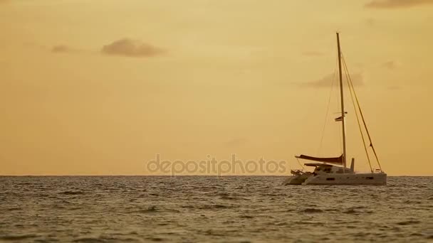 Tramonto sulla spiaggia di Naiharn. Lo yacht a vela ondeggia sulle onde. Nuvoloso su sfondo arancio tramonto . — Video Stock