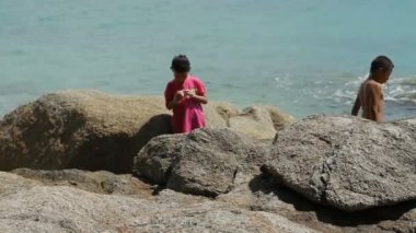 Phuket, Tayland - 18 Kasım 2012. Yerel çocuklar denizde kayalar üzerinde oynarken sörf. Laem Ka Noi beach.