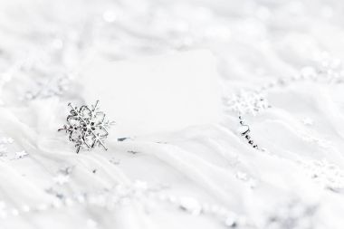 Parlak gümüş kar taneleri, Noel süsleri ve metniniz için boş kağıda beyaz tatil arka plan. Açık ziyaret kart yeni yıl kumaş arka plan üzerinde.