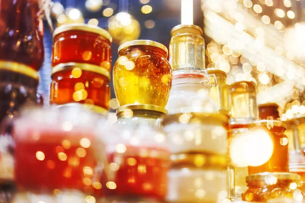 Foire des fêtes. Pots de miel luisant dans des guirlandes d'ampoule — Photo