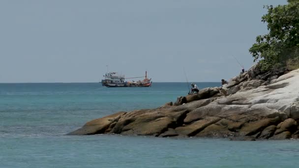 Phuket, thailand - 18. november 2012. männer angeln am strand. Fischerboot wiegt sich auf den Wellen. — Stockvideo