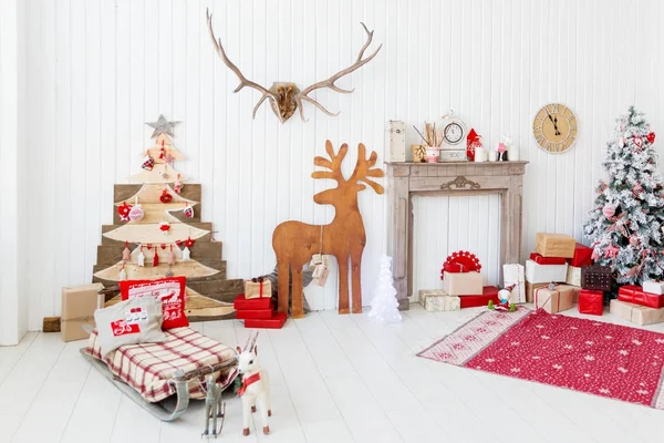 Noël et Nouvel An détails de l'intérieur de la maison cerf en bois, cheminée avec bougies, arbre Eve et cadeaux . — Photo
