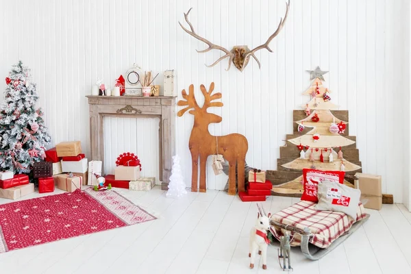 Noël et Nouvel An détails de l'intérieur de la maison cerf en bois, cheminée avec bougies, arbre Eve et cadeaux . — Photo