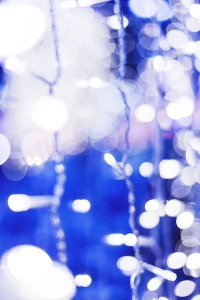 Defocused nacht straatverlichting, wazig kleurrijke bokeh achtergrond. Vakantie kleurrijke lantaarns en gloeilampen slingers. — Stockfoto