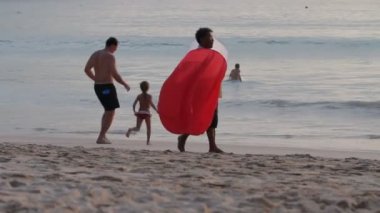 Phuket, Tayland - 18 Kasım 2012. Baba ile kızı yürüme. Yerel adam Çin uçan kağıt fenerler satıyor. Nai Harn beach.