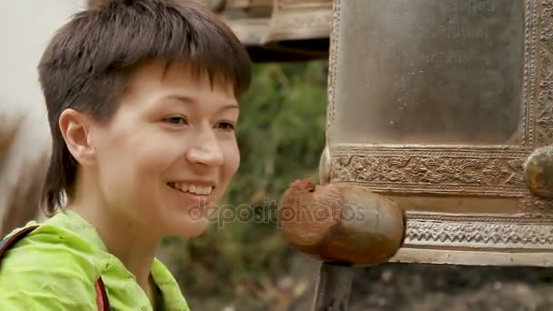 バンコク, タイ王国 - 2012 年 10 月 24 日。女性は仙骨の鐘を木製ハンマーでノックします。ワット サケット ラチャプ ウォラ ブラ マハ ウィハン、ゴールデン マウント . — ストック動画
