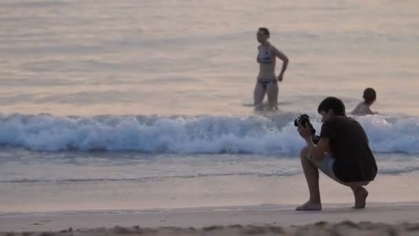 PHUKET, THAÏLANDE - 18 novembre 2012. Femme tirant des vagues de mer au coucher du soleil sur la plage de Nai Harn. Touristes se baignant dans la mer surf . — Video