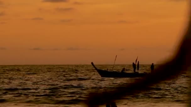 Superbe coucher de soleil sur la plage de Naiharn. Groupe de personnes sur le bateau passant par là. Paysage nuageux sur fond de coucher de soleil orange . — Video