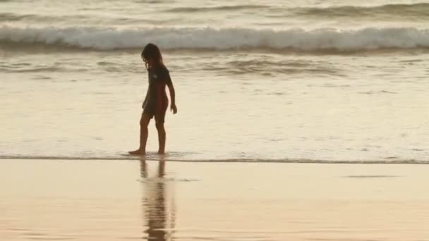 Phuket, Thailand - 18 November 2012. Flicka som leker i havet surf. Orange solnedgång reflektion i havets vågor. — Stockvideo