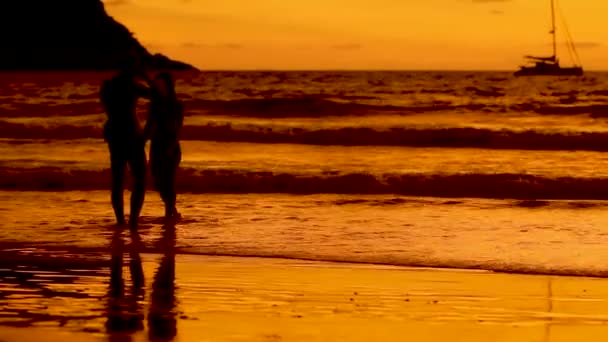 Lindo pôr do sol na praia de Naiharn. Casal jovem atirando uns nos outros no fundo do pôr-do-sol laranja. Praia de Nai Harn, Phuket, Tailândia . — Vídeo de Stock