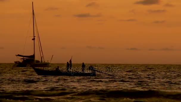 Hermosa puesta de sol en la playa de Naiharn. Un grupo de personas en el barco de paso. Paisaje nublado sobre fondo naranja al atardecer . — Vídeos de Stock