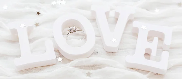 Word LOVE sobre fondo de tela blanca con anillo de diamantes de compromiso. Bueno para las tarjetas de San Valentín. Lugar para el texto . — Foto de Stock