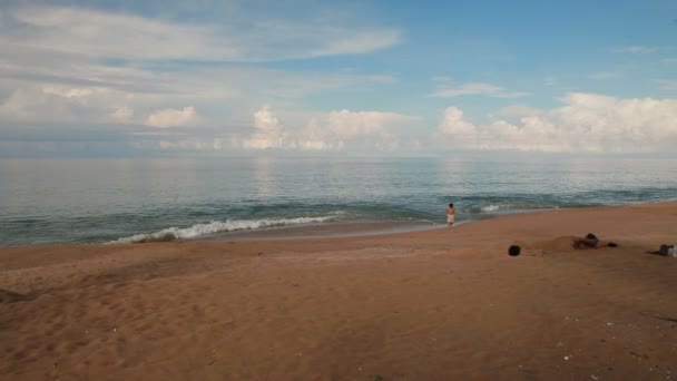 PHUKET, TAILANDIA - 25 de noviembre de 2012. Niño caminando en el mar surf. Día soleado en la isla de Phuket, Tailandia . — Vídeo de stock