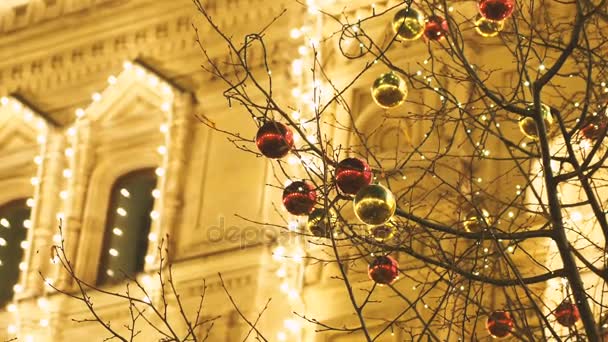 Calles de Moscú decoradas para la celebración de Año Nuevo y Navidad. Árbol con bolas de color rojo brillante y amarillo. GUM Tienda Principal con bombillas en el fondo. Rusia . — Vídeos de Stock