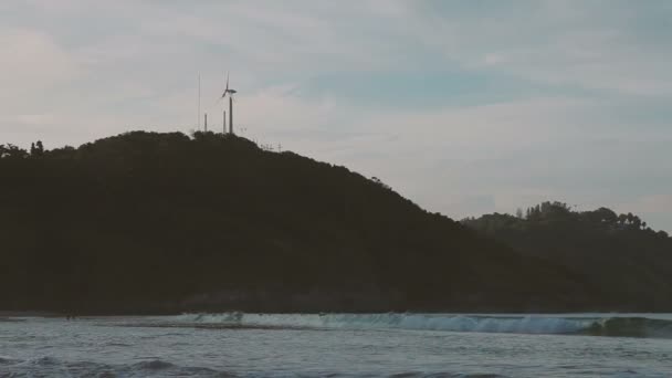 Coucher de soleil sur la plage Nai Harn. Vue sur éolienne sur colline. Phuket, Thaïlande .