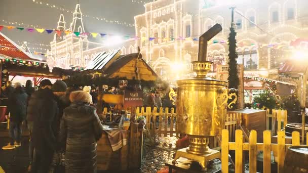 Moskou, Rusland - 03 December 2017: Mensen lopen op kerstmarkt op het Rode plein. Straat cafe met lichte gouden Samowar. — Stockvideo