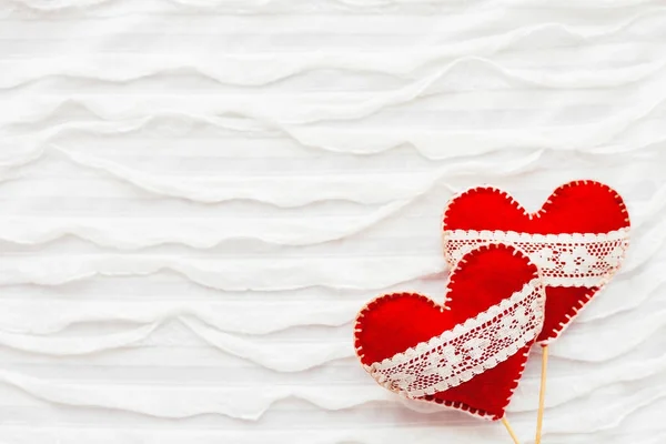 Fond en tissu blanc avec rouche.Deux cœurs en feutre avec des lacets, symbole de l'amour. Bon pour les cartes de Saint-Valentin. Place pour le texte . — Photo