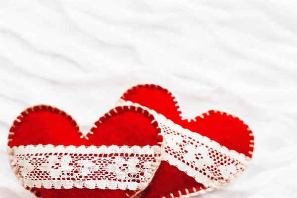 Fondo de tela blanca con ruche.Dos corazones de fieltro con cordones, símbolo del amor. Bueno para las tarjetas de San Valentín. Lugar para el texto . — Foto de Stock