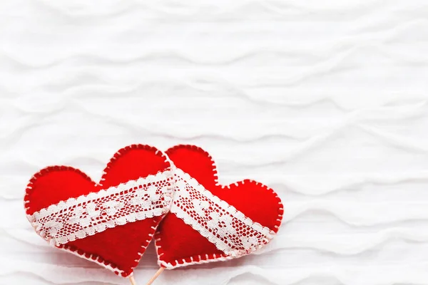 Fond en tissu blanc avec rouche.Deux cœurs en feutre avec des lacets, symbole de l'amour. Bon pour les cartes de Saint-Valentin. Place pour le texte . — Photo
