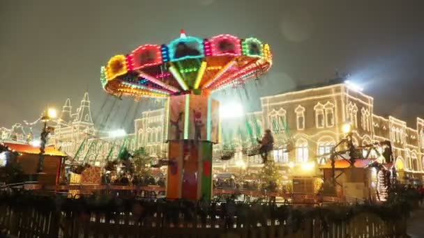 MOSCÚ, RUSIA - 03 de diciembre de 2017: Colorido carrusel iluminado en la feria de Navidad en la Plaza Roja. Edificios y árboles decorados para la celebración de Año Nuevo . — Vídeos de Stock