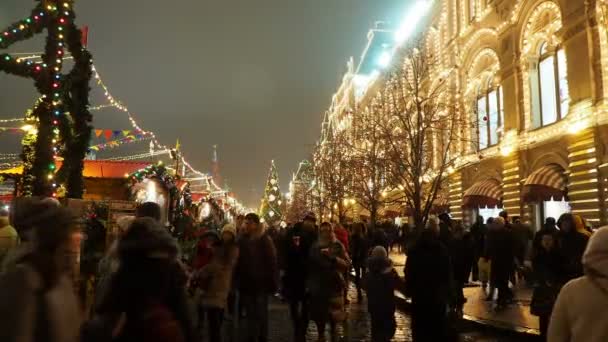 МОСКВА, РОССИЯ - 14 декабря 2017 года: Люди на Рождественской ярмарке возле Главного универмага на Красной площади. Здания и деревья украшены и освещены к празднованию Нового года . — стоковое видео