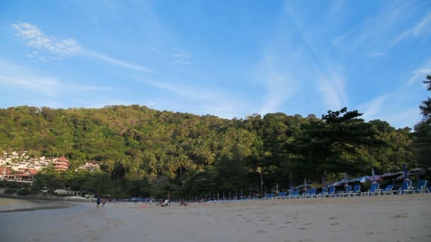 Plage de Nai Harn sur l'île de Phuket. Rangées de chaises longues sur sable. Vue sur la colline. Les gens loin sur la plage font des exercices. Thaïlande . — Video