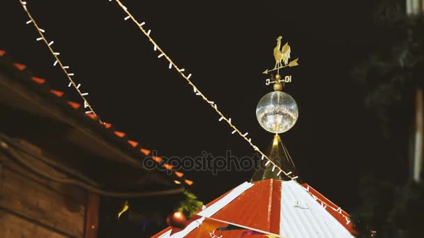 Christmas fair on Red Square. Buildings and trees decorated and illuminated for New Year celebration. Weathervane with rooster figure and shining mirror discoball. Russia. — Stock Video