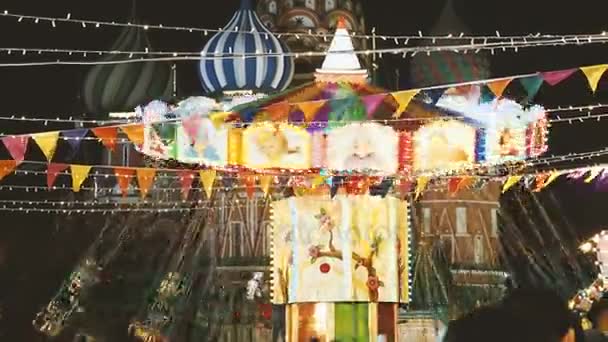 Moskva, Ryssland - 03 December 2017: Färgglada belysta carousel på Julmarknad på Röda torget. Byggnader och träd är inrett för nyårsfirande. — Stockvideo