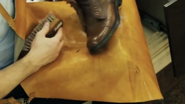 Шифер для взуття відполірує чоботи з коричневої шкіри спеціальним пензлем — стокове відео