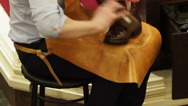 Shoe shiner polishes the boots of brown leather with a special brush — Stock Video