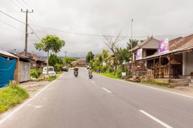 Bali, Endonezya - 30 Ocak 2013. Erkekler bir stereo bisikletle taşırlar. Sürücü Köyü üzerinden motosiklet sürüş.