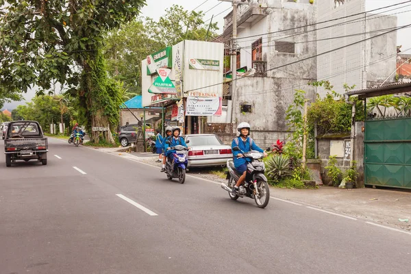 BALI, INDONESIA - 30 de enero de 2013. La vida callejera habitual en Bali. Estudiantes y alumnos conducen bicicletas . — Foto de Stock