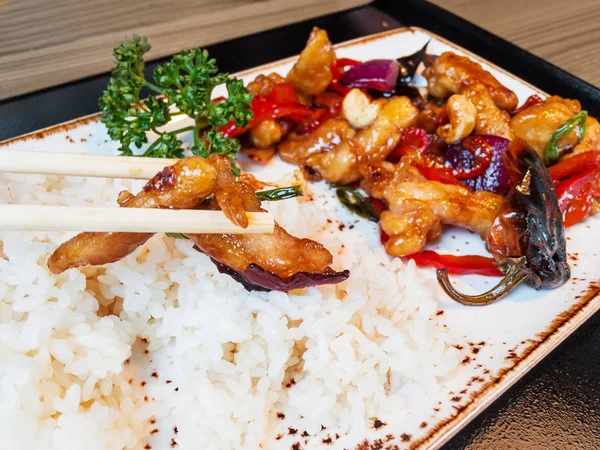 Asian cuisine - Tori no casu. Fried chicken meat with cashew nuts and pepper in hot sauce, boiled rice. — Stock Photo, Image