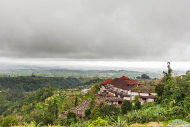 Panorama görünüm Köyü ve tarım pirinç tarlaları tepe üzerinde bina. Kış bulutlu ve yağmurlu mevsim. Bali Adası, Endonezya.