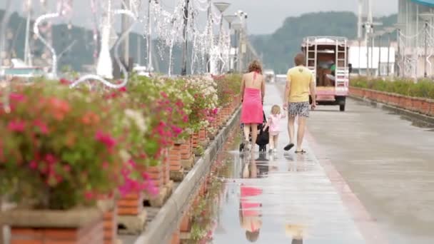 PHUKET, THAILAND - 24 de novembro de 2012. Família andando no cais de Chalong após a chuva. Mãe rola carrinho de bebê, pai leva bebê menina pela mão . — Vídeo de Stock