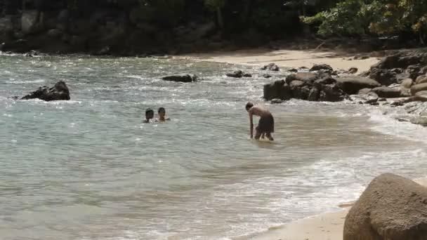 Phuket, Thailand - 18 November 2012. Lokala barn som leker på klipporna i havet surfa. Laem Ka Noi beach. — Stockvideo