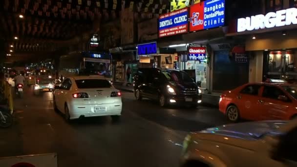 BANGKOK, THAILAND - 20 de outubro de 2012. Tráfego noturno em Bangkok. Carros dirigindo lojas passadas, clínicas, estúdio de tatuagem . — Vídeo de Stock