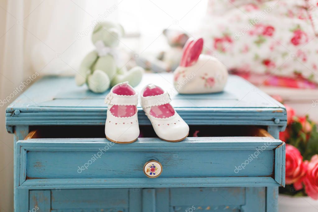 Cute leather booties for little girl. White accessory for girl outfit. Tiny shoes on wooden background.