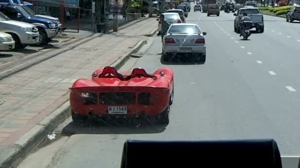 BANGKOK, TAILANDIA - 25 de octubre de 2012. Calles de Bangkok a través de la ventana delantera de un autobús en movimiento. Coche deportivo rojo de moda . — Vídeos de Stock