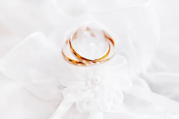 Paar Gouden trouwringen op kant zijde stof met bloem van stof. Bruiloft borduren jurk detail. — Stockfoto