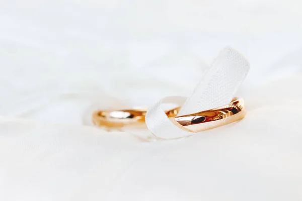 Golden wedding rings on white silk background. Wedding details. Symbol of love and marriage. — Stock Photo, Image