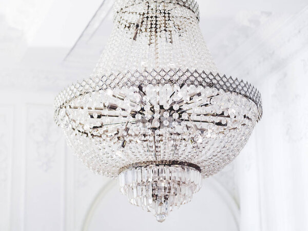 Большая многоуровневая люстра со стеклянными подвесками. Элемент интерьера с хрустальными деталями в белой комнате
.
