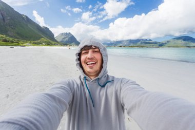 Turist adam Lofoten Adaları Rambergstranda sahilde selfie yapma. Güzel kumlu plajı ve masmavi su. Norveç.