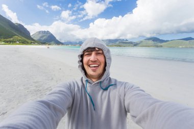Turist adam Lofoten Adaları Rambergstranda sahilde selfie yapma. Güzel kumlu plajı ve masmavi su. Norveç.